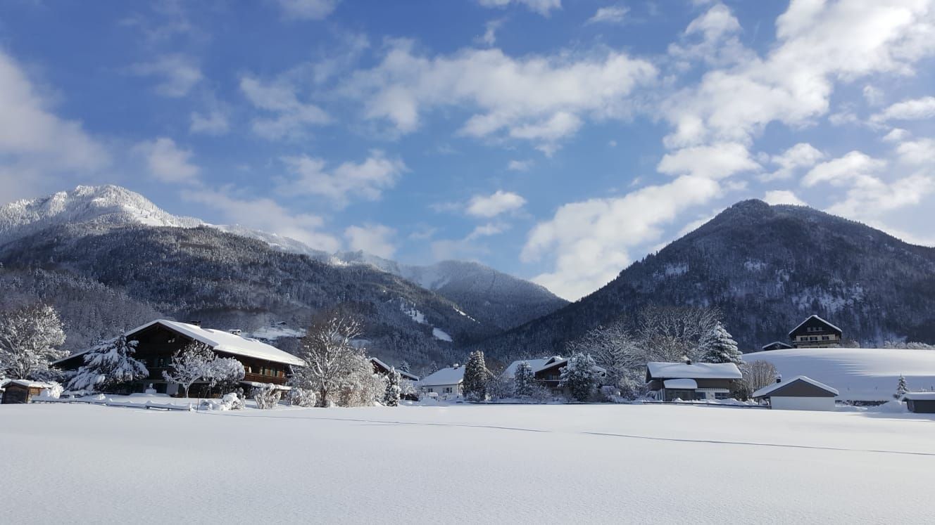 Un pueblo cubierto de nieve con casas de madera y montañas al fondo.