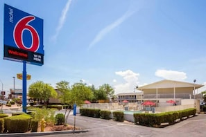 A motel sign with a pool area and a building with a covered patio.