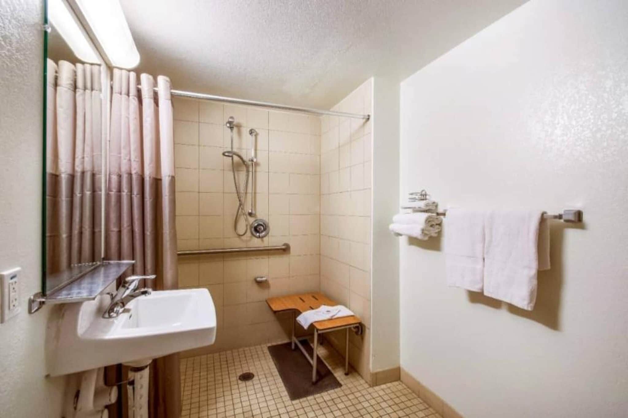 A small, compact bathroom with a sink, shower, and a towel rack.