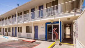 Un motel con un letrero azul que dice 'Welcome', una oficina y un estacionamiento.