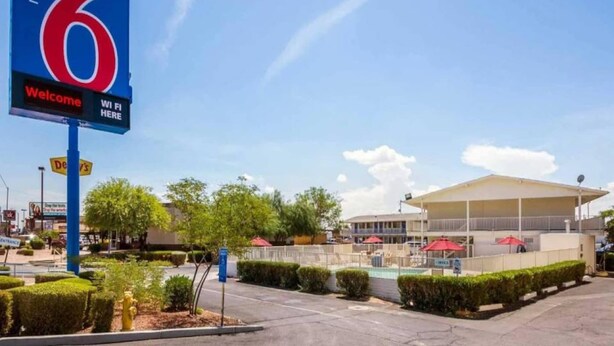 Señal de motel que muestra un área de piscina y un edificio con porche cubierto.