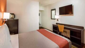 Ein Hotelzimmer mit Bett, Schreibtisch, Stuhl, Fernseher und Spiegel.