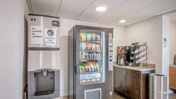 Máquina expendedora con snacks y bebidas frías, una máquina de café y un dispensador de agua en un entorno comercial.