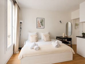 Una habitación de hotel con cama, mesita de noche, espejo y ventana con cortinas.