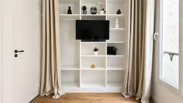 A room with a white built-in TV shelf, wooden flooring, and a door with a handle.