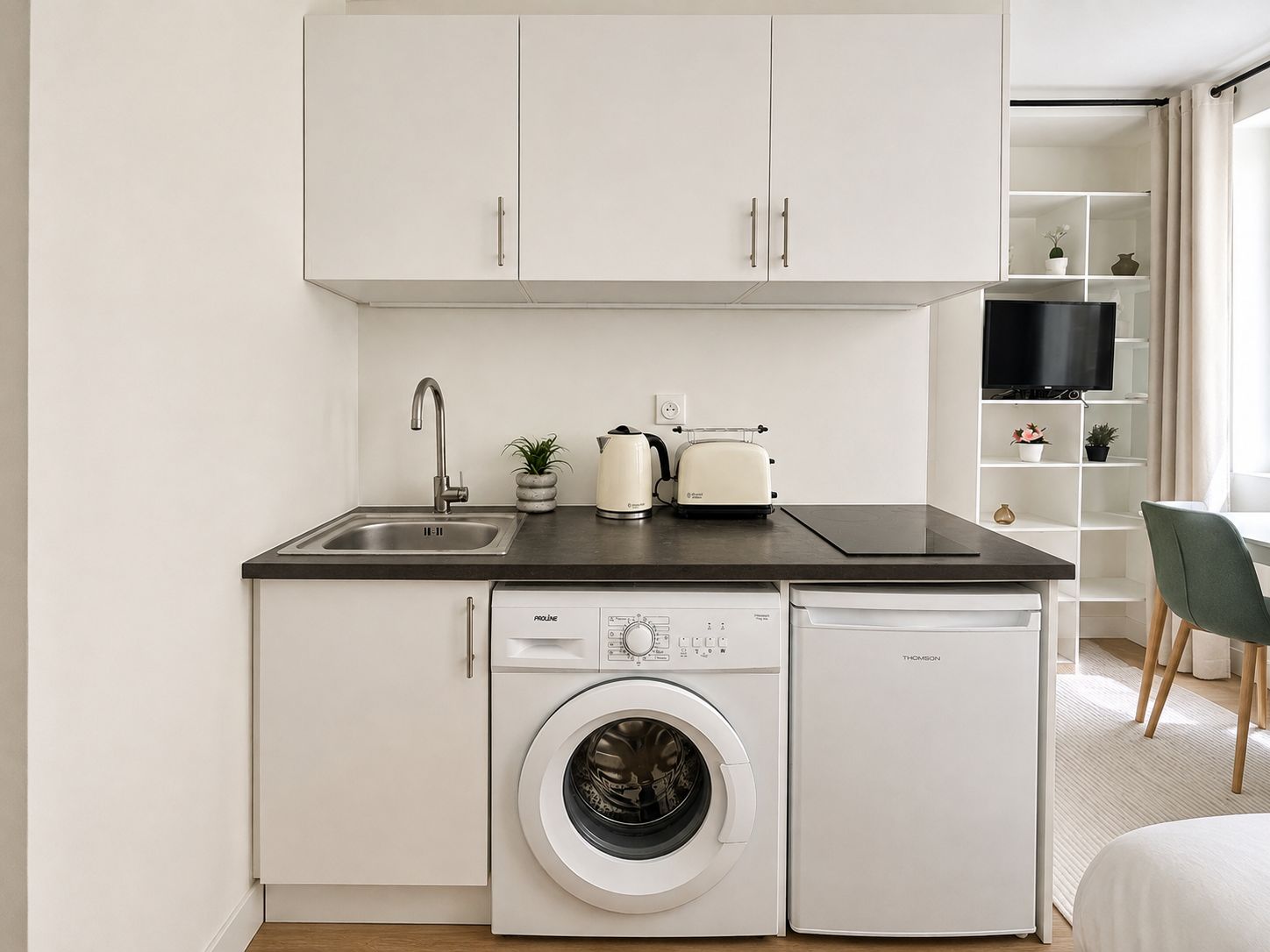 A compact kitchen with a washing machine, a toaster, and a sink.