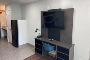 A modern kitchen with a built-in refrigerator, a flat-screen TV mounted on the wall, and a small desk with a chair. - 1 Queen Bed| Nsmk Kitchen, Sofa-Bed (Peoria IL)