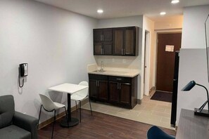 A compact kitchen with dark cabinets, a white countertop, and a small dining area with a table and chairs.