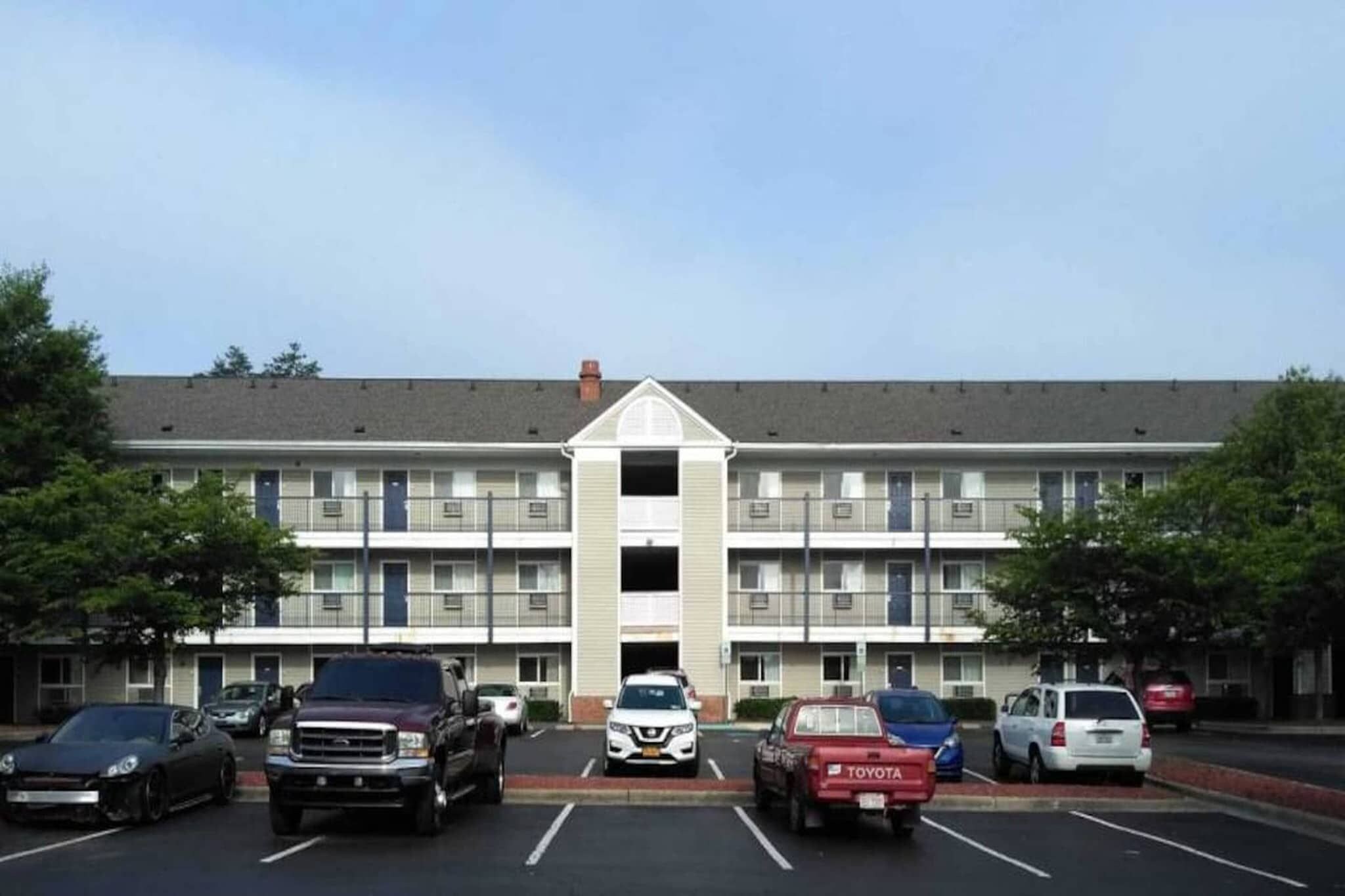 Ein mehrgeschossiges Hotel mit zentralem Eingang und Parkplatz.