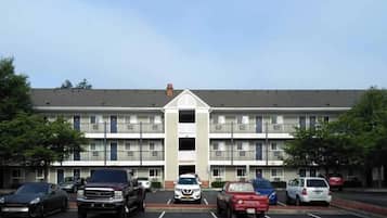 A multi-story hotel with a central entrance and parking lot.