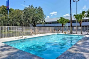 A rectangular swimming pool with a white fence, lounge chairs, and a palm tree in the background. - 2 Full Beds | Non-Smoking, Kitchen (Jacksonville)