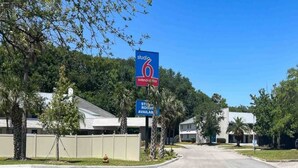 A Studio 6 extended stay hotel with a clear road in front, surrounded by trees and residential buildings. - 2 Full Beds | Non-Smoking, Kitchen (Jacksonville)