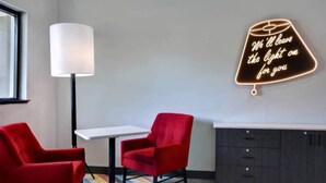 A modern room with a white table, two red chairs, a floor lamp, and a neon sign on the wall. - 2 Full Beds | Non-Smoking, Kitchen (Jacksonville)