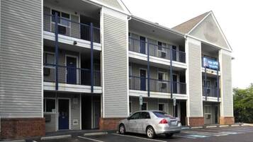 A multi-story hotel with a parking lot and a car parked in front.