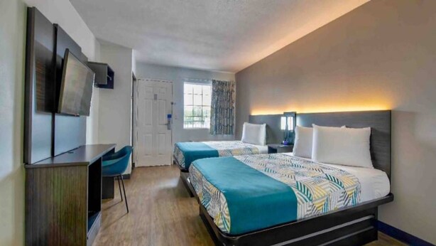 Hotellihuone, jossa on kaksi sänkyä, työpöytä, televisio ja ikkuna.