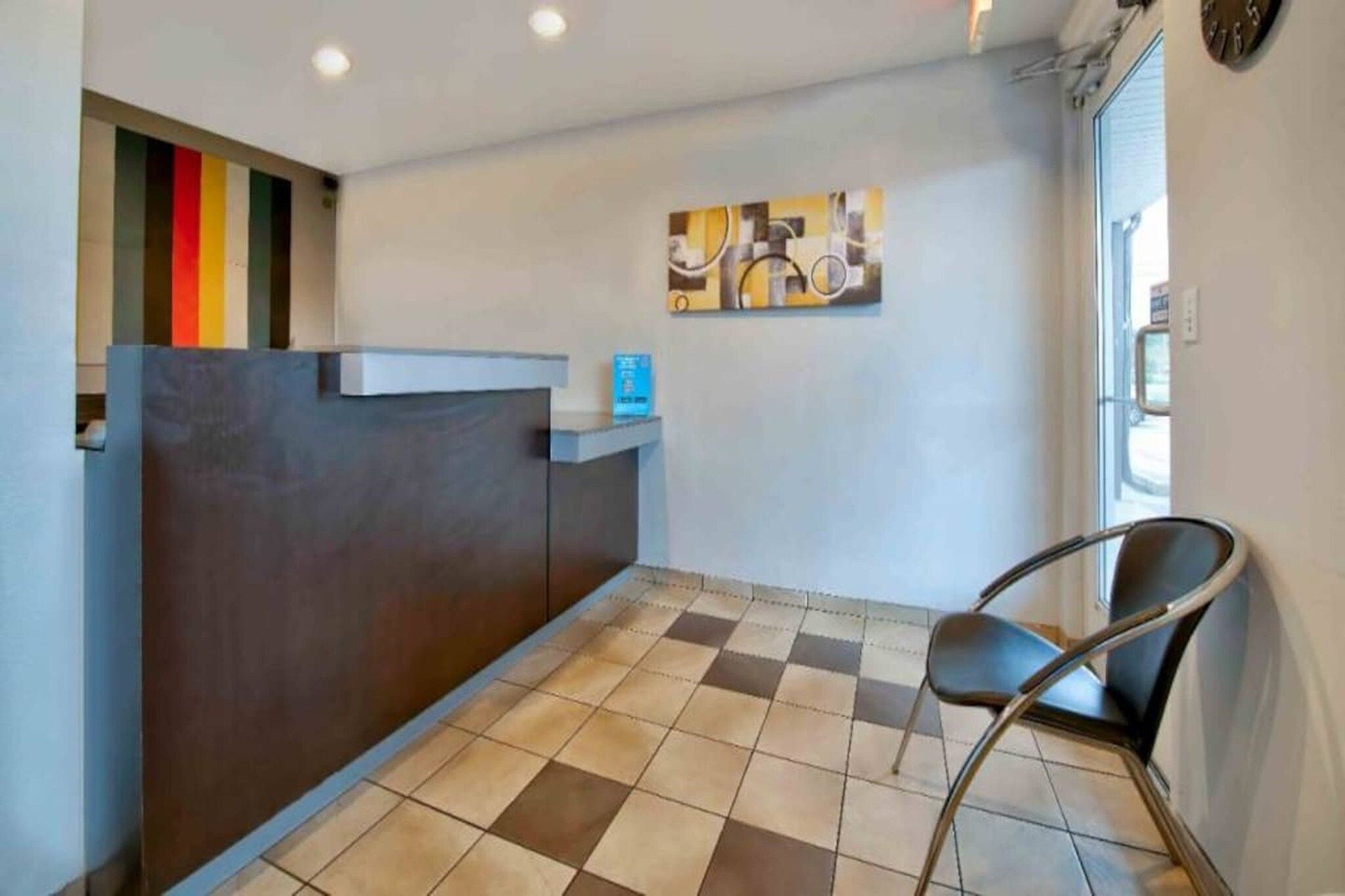 A reception area with a checkered floor, a reception desk, a chair, and a wall-mounted clock.