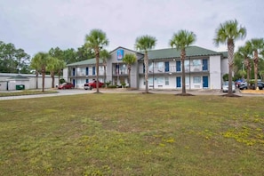 A motel with a two-story structure, a parking lot, and several palm trees. - 2 Full Beds | Non-Smoking (Pascagoula)