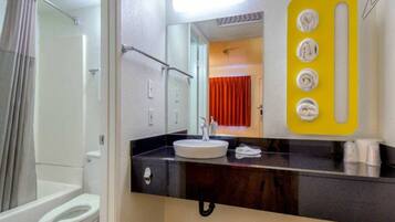 Een badkamer met een douche, een wastafel en een spiegel met een geel paneel.