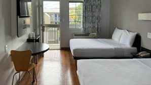Ein Hotelzimmer mit zwei Betten, einem Tisch, einem Stuhl und Blick ins Freie.