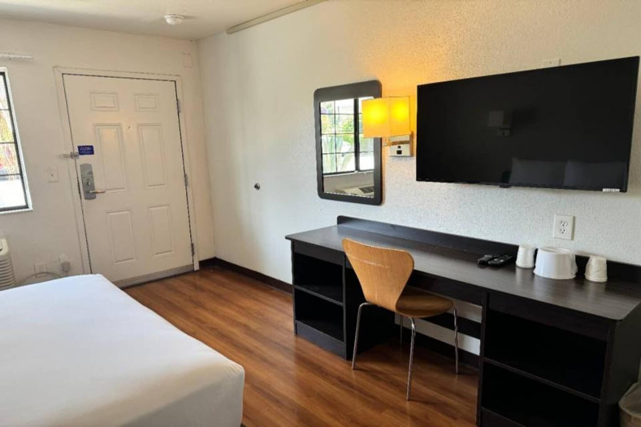 A hotel room with a bed, a desk with a chair, a television, and a window.