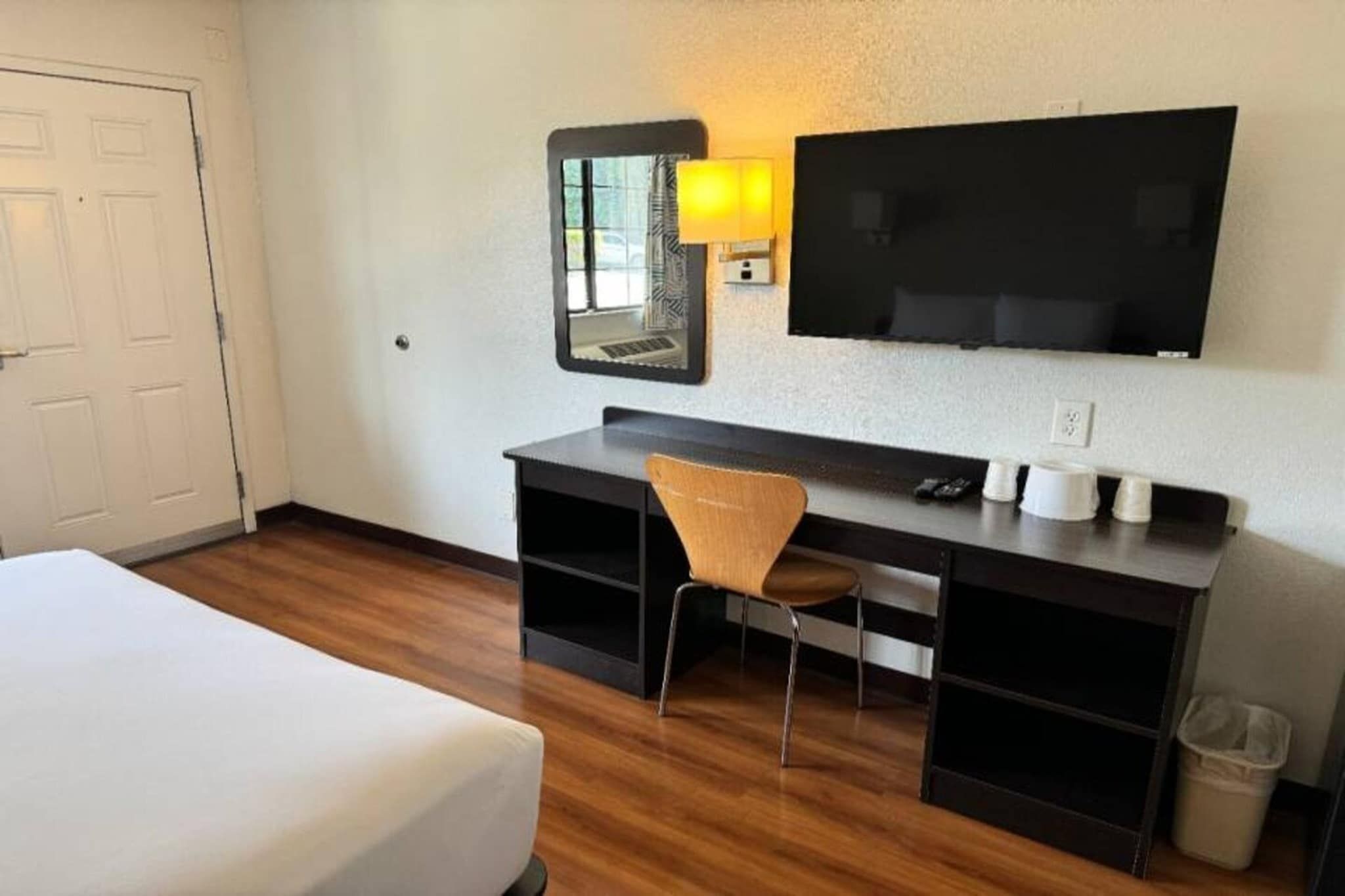 Ein Hotelzimmer mit einem Bett, einem Schreibtisch, einem Stuhl, einem Fernseher und einem Mülleimer.