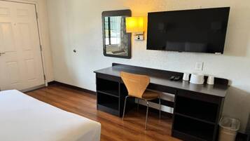 Ein Hotelzimmer mit einem Bett, einem Schreibtisch, einem Stuhl, einem Fernseher und einem Mülleimer.
