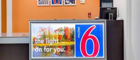 A reception desk with a sign that reads 'We'll leave the light on for you.'