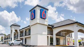 A 6 Motel with a two-story building, a parking lot, and a covered entrance.