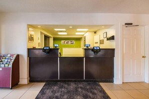 A reception area with two counters, a check-in kiosk, a reception desk, and a door. - 2 Full Beds | Non-Smoking (Greensboro)