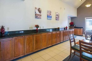 A kitchen with wooden cabinets, a black countertop, and a dining area with chairs. - 2 Full Beds | Non-Smoking (Greensboro)