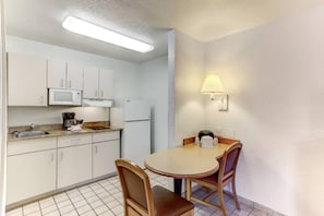 A compact kitchen with white cabinets, a microwave, a refrigerator, and a dining table with two chairs. - 1 Queen Bed|Micfridge,Smoking (Kissimmee)