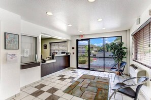 A reception area with a check-in counter, a waiting area with chairs, and a view of the outside through large glass doors. - 1 Queen Bed|Micfridge,Smoking (Kissimmee)