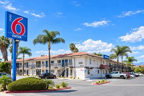Ein Motel mit rotem Dach, Palmen und blauem Himmel.