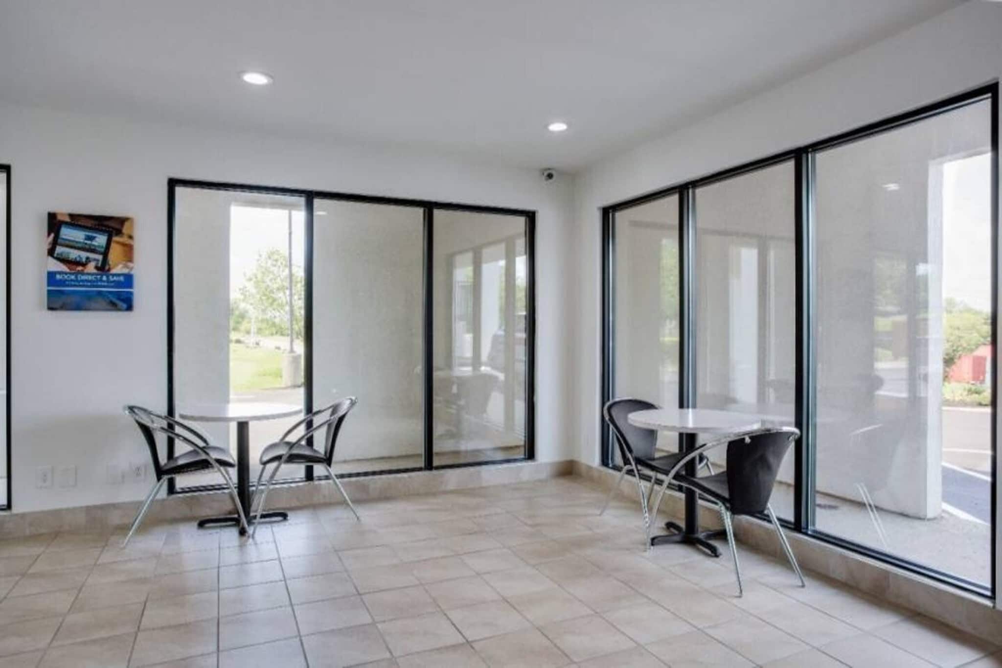 A spacious room with large windows, a tiled floor, and two tables with chairs.