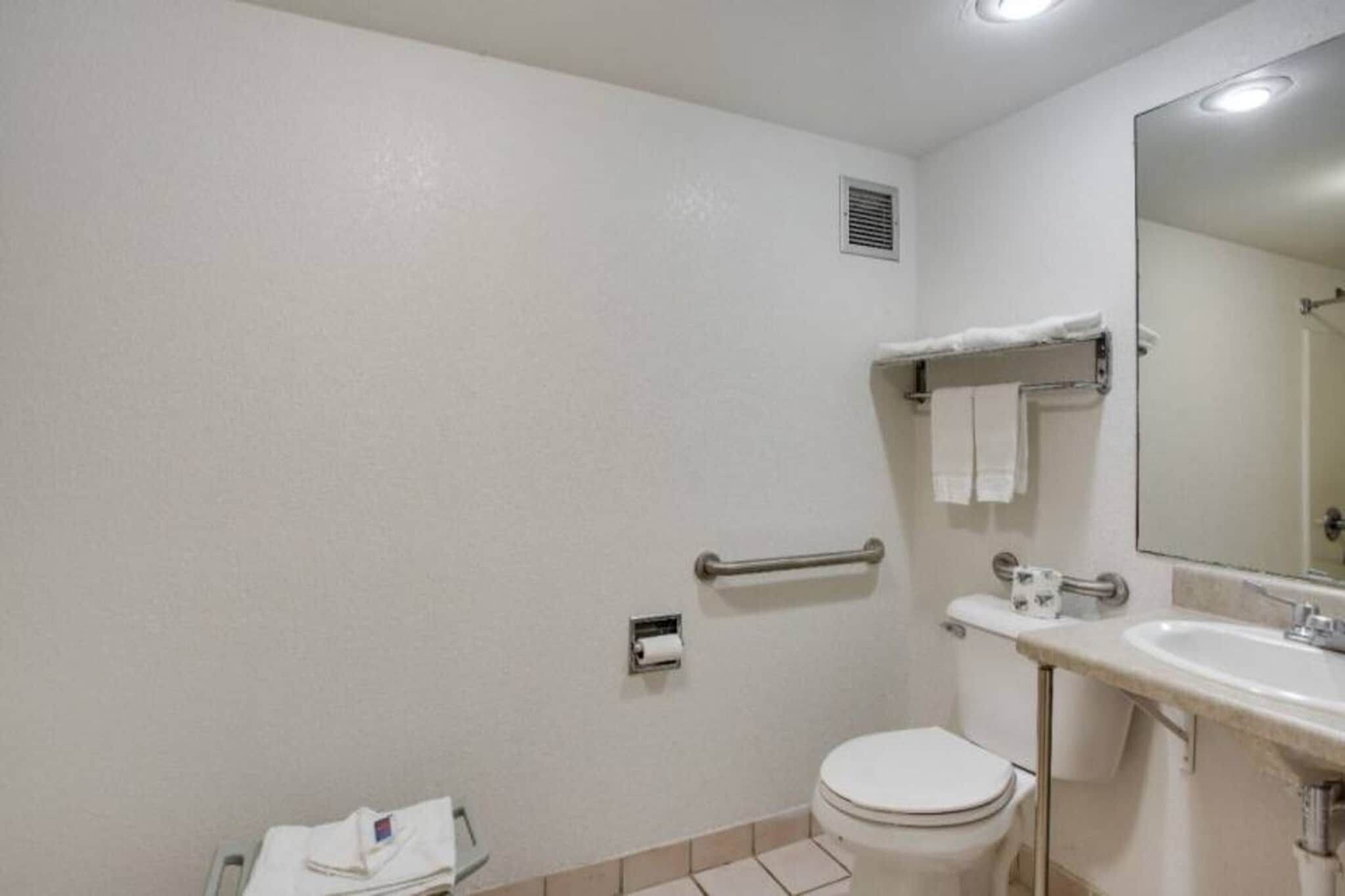 A standard bathroom with a toilet, sink, mirror, and towel rack.