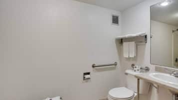 A standard bathroom with a toilet, sink, mirror, and towel rack.