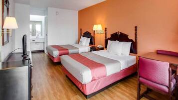 A hotel room with two beds, a desk, a chair, and a television.