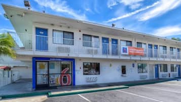 A motel with a '6' sign, a 'Welcome' sign, and a banner advertising room rates.