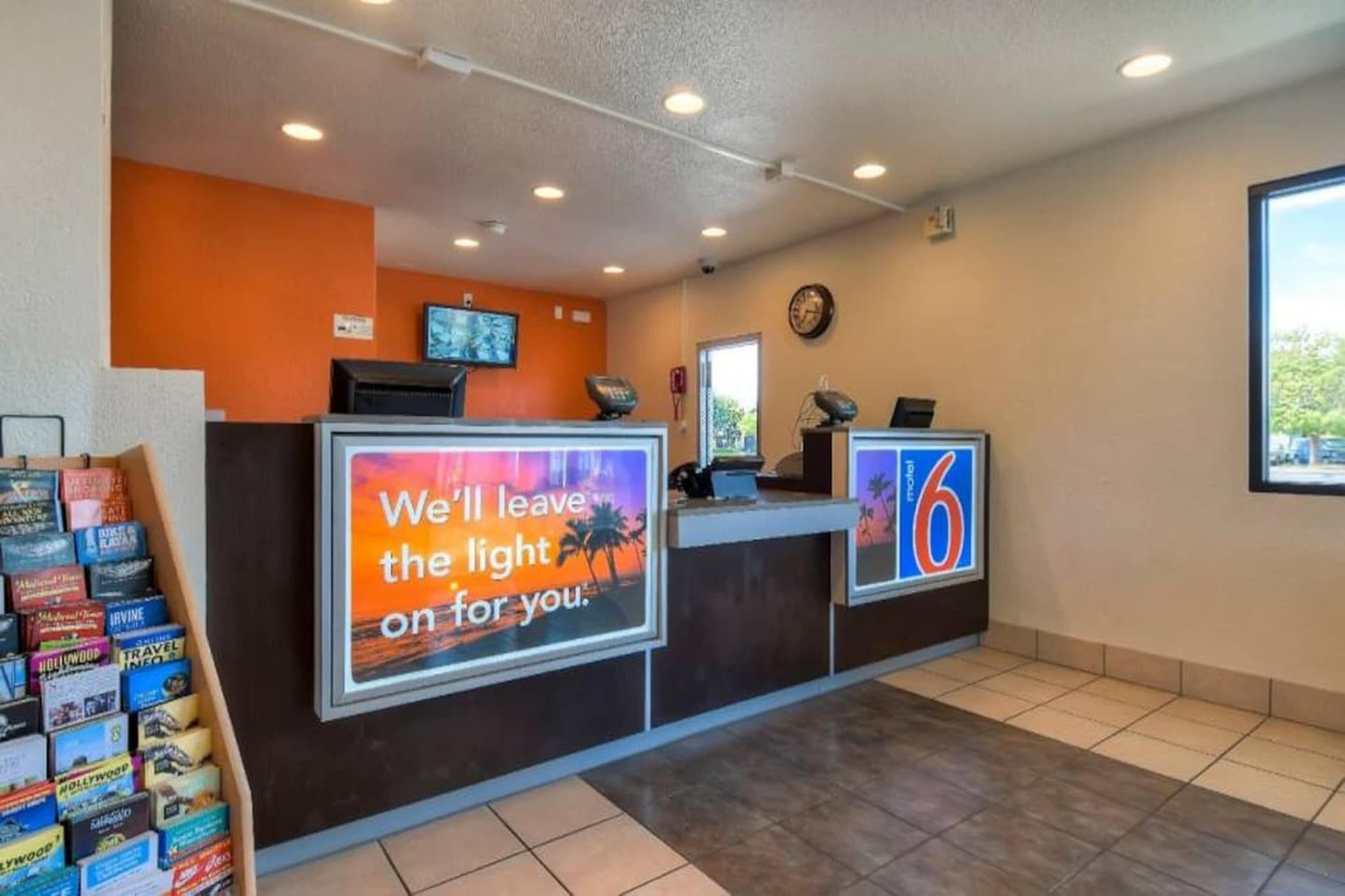 Een hotel receptie met een groot bord waarop staat: 'Wij laten het licht voor je aan'.
