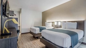 Een hotelkamer met twee bedden, een bureau en een lamp.