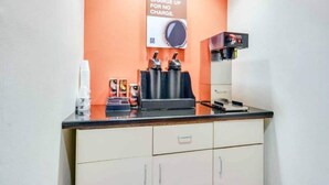 Kaffestation med kaffemaskine, kopper og skilt, der tilbyder gratis morgenkaffe.