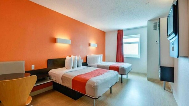 Quarto de hotel com duas camas, uma escrivaninha e uma televisão.