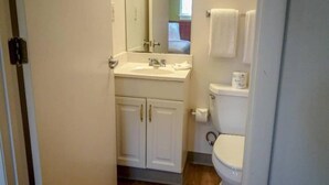 Un baño pequeño con lavamanos, espejo, inodoro y armario.