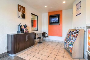 A small reception area with a counter, chairs, a television, and a magazine rack.
