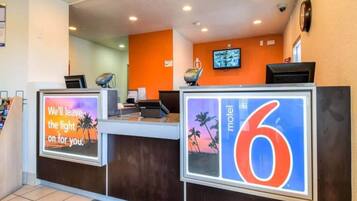 A hotel reception desk with a large sign indicating room number 6, a digital display, and a television mounted on the wall.