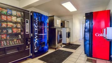 Un espace de vente proposant des boissons, avec un distributeur de boissons énergisantes Powerade, un réfrigérateur et un distributeur de boissons Coca-Cola.