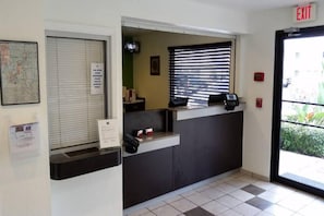 A reception desk with a map, a sign, a window with blinds, and an exit sign. - 1 Queen Bed | Non-Smoking (Kissimmee)