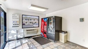 Habitació amb zona de seients, m àquina expenedora, televisió penjada a la paret i un cartell publicitari de productes de neteja.
