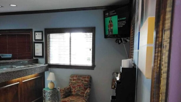 Habitación con barra, ventana con persianas, televisión montada en la pared y una silla estampada.