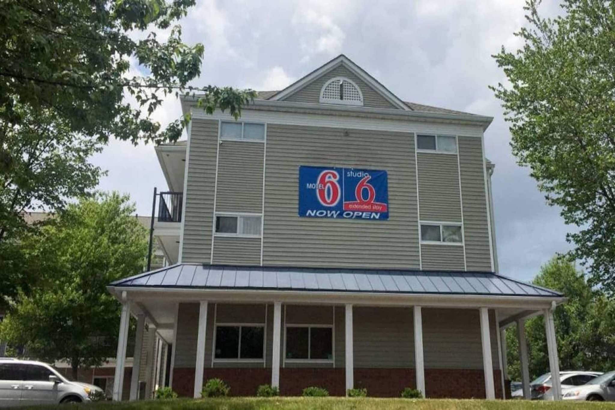 A two-story motel with a blue sign indicating it's now open.